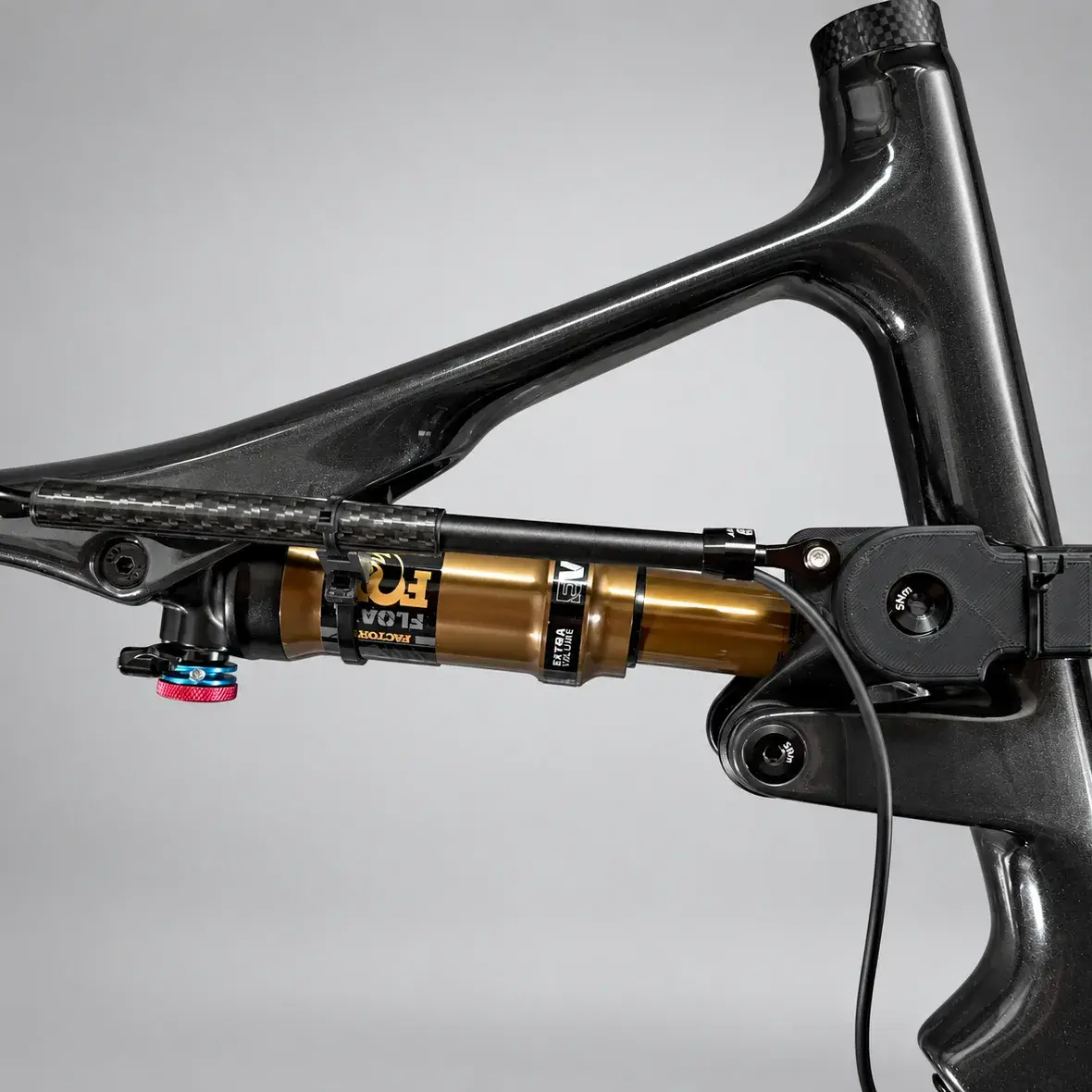 A Cannondale Scalpel carbon frame with a printed swingarm bracket and linear sensor fitted beside the Fox Float Factory rear shock, against a grey background.