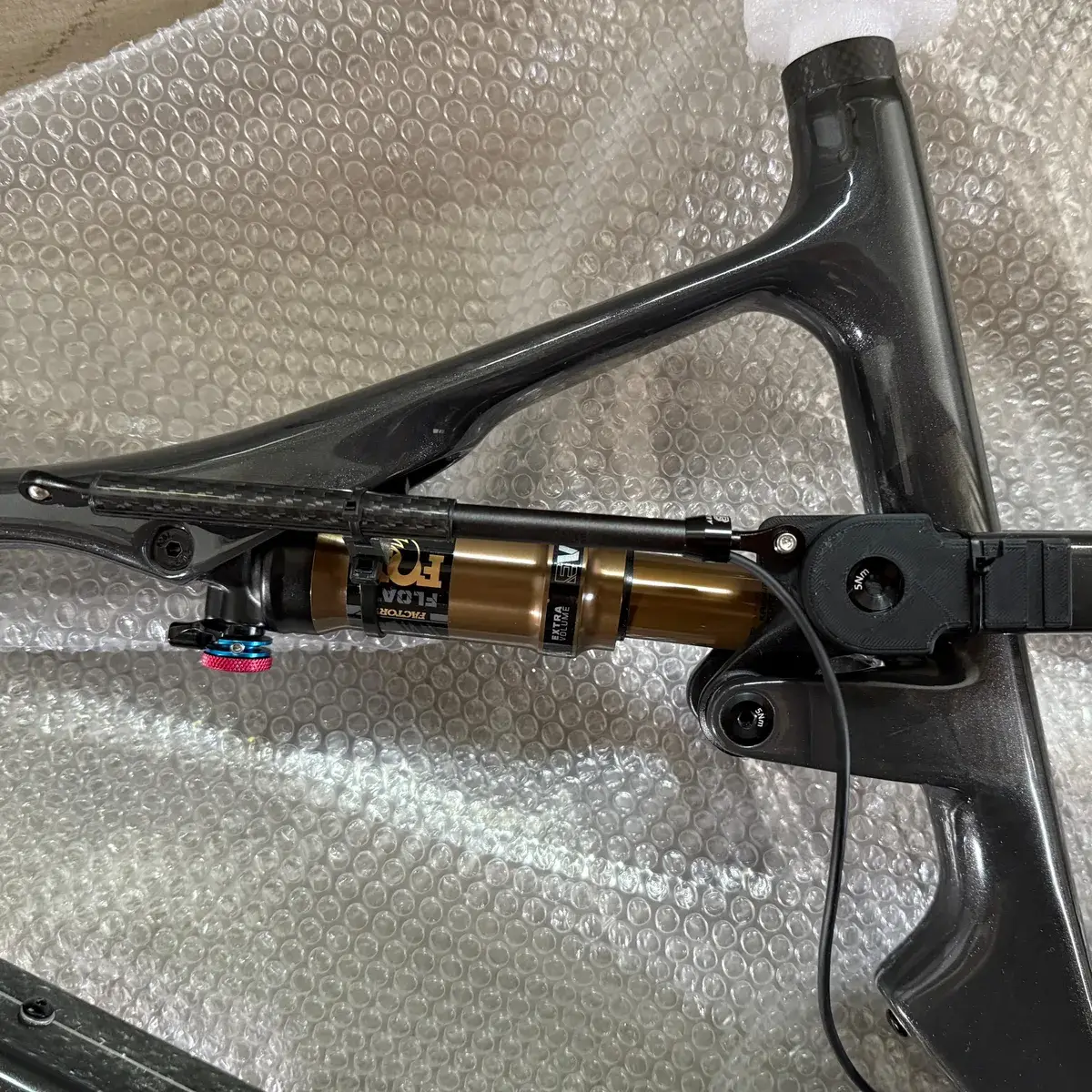 A Cannondale Scalpel carbon frame on a bench, with the printed bracket bolted beside the Fox Float Factory rear shock and the sensor cable running away from it.