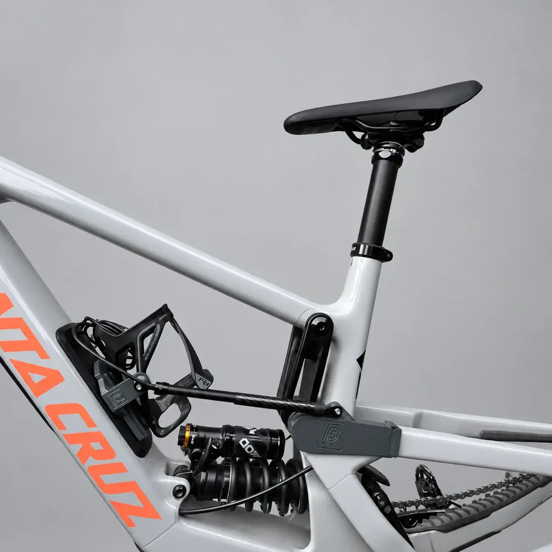 A grey Santa Cruz frame with a linear rear sensor attached to the printed link mount beside the coil shock, and the opposite sensor end beside the bottle cage holder.