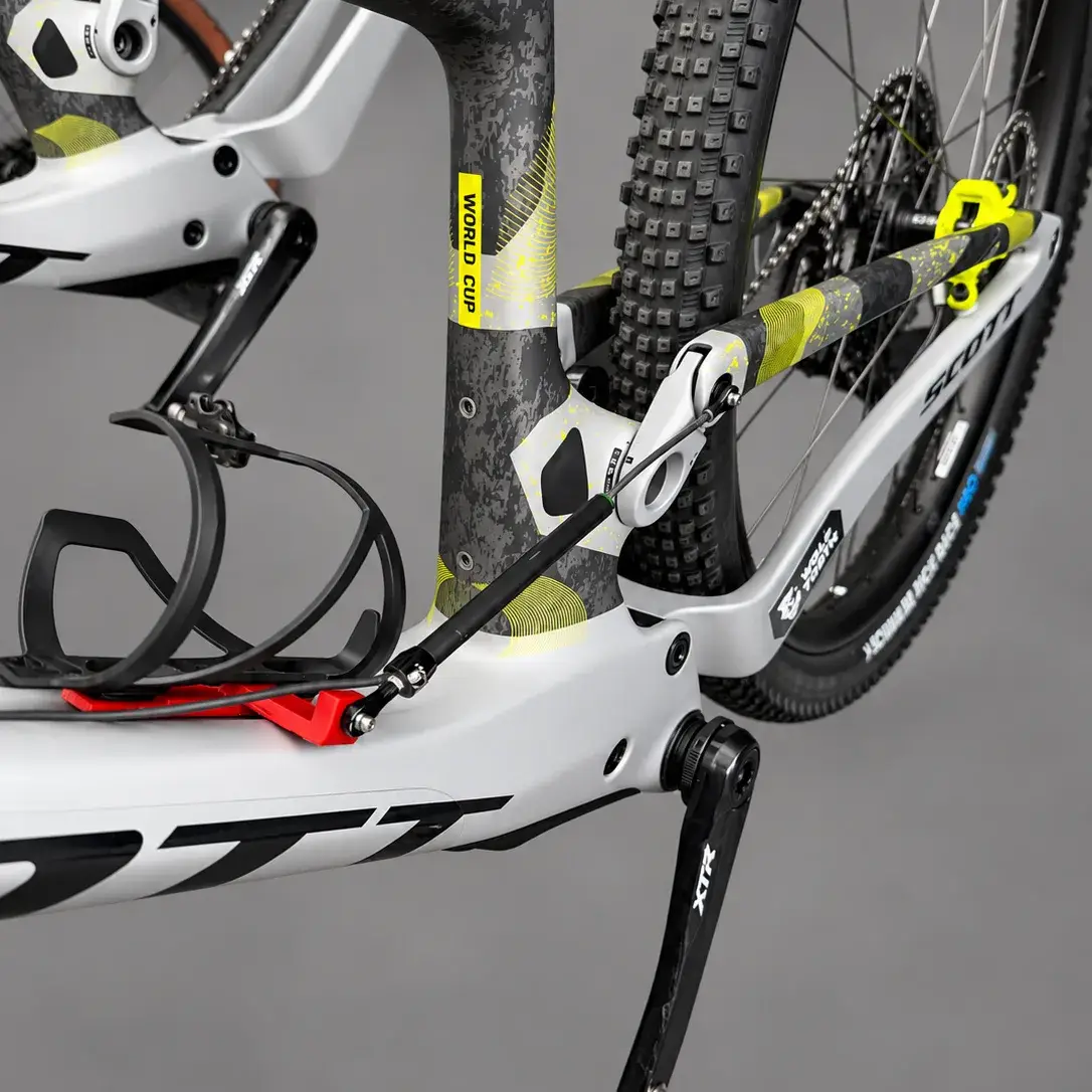 A Scott Spark with a red printed swingarm bracket and linear sensor fitted along the frame, against a grey background. The rear shock is hidden inside the frame.
