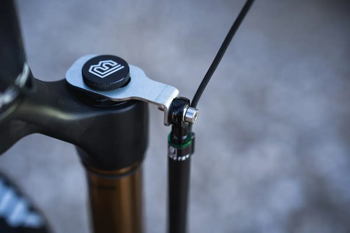 The upper mount of a BYB Telemetry fork sensor on a mountain bike fork crown, the ball joint and cable running down beside the stanchion.