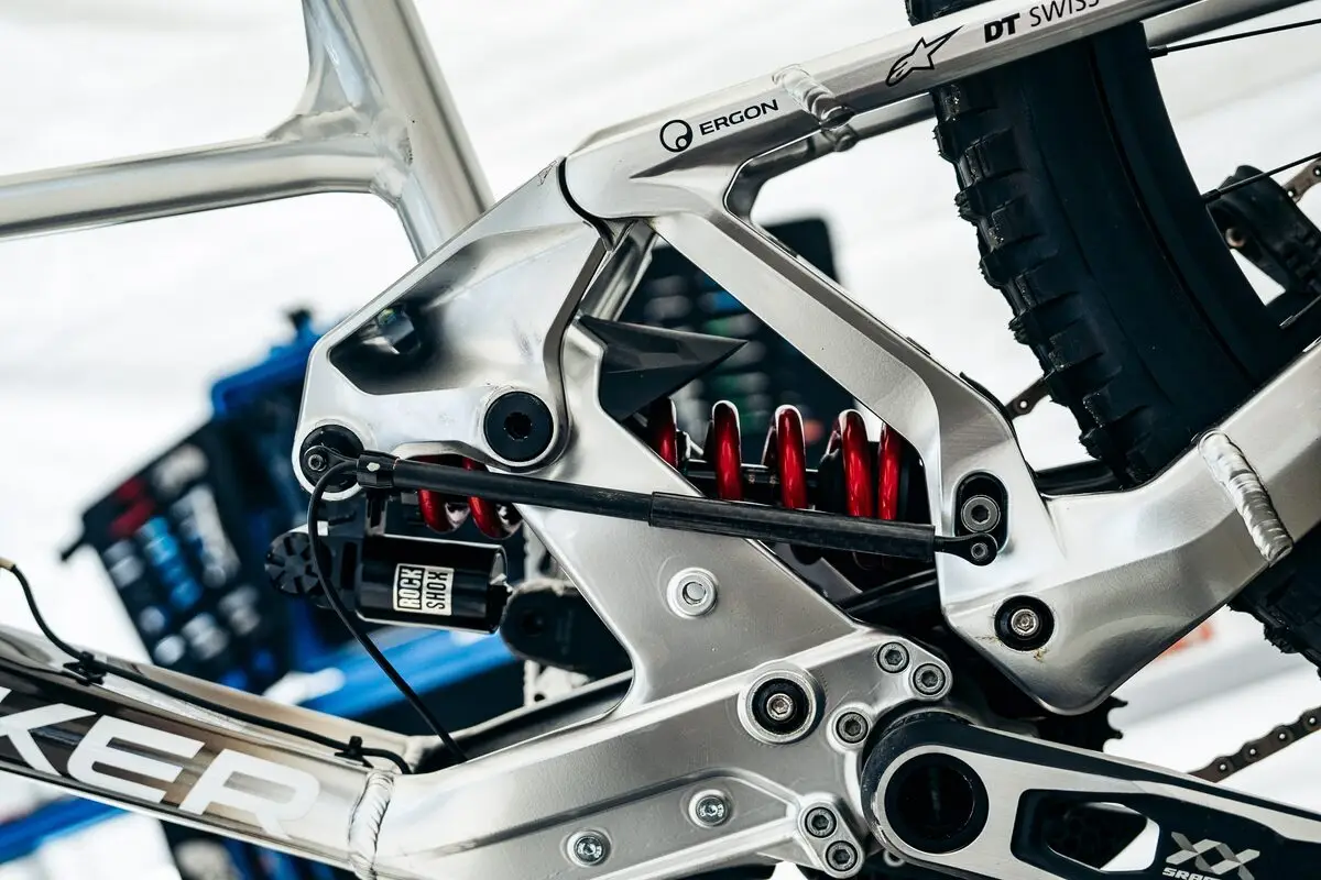 A BYB Telemetry shock sensor fitted diagonally across the coil shock of a downhill mountain bike, between the linkage and the lower shock mount.