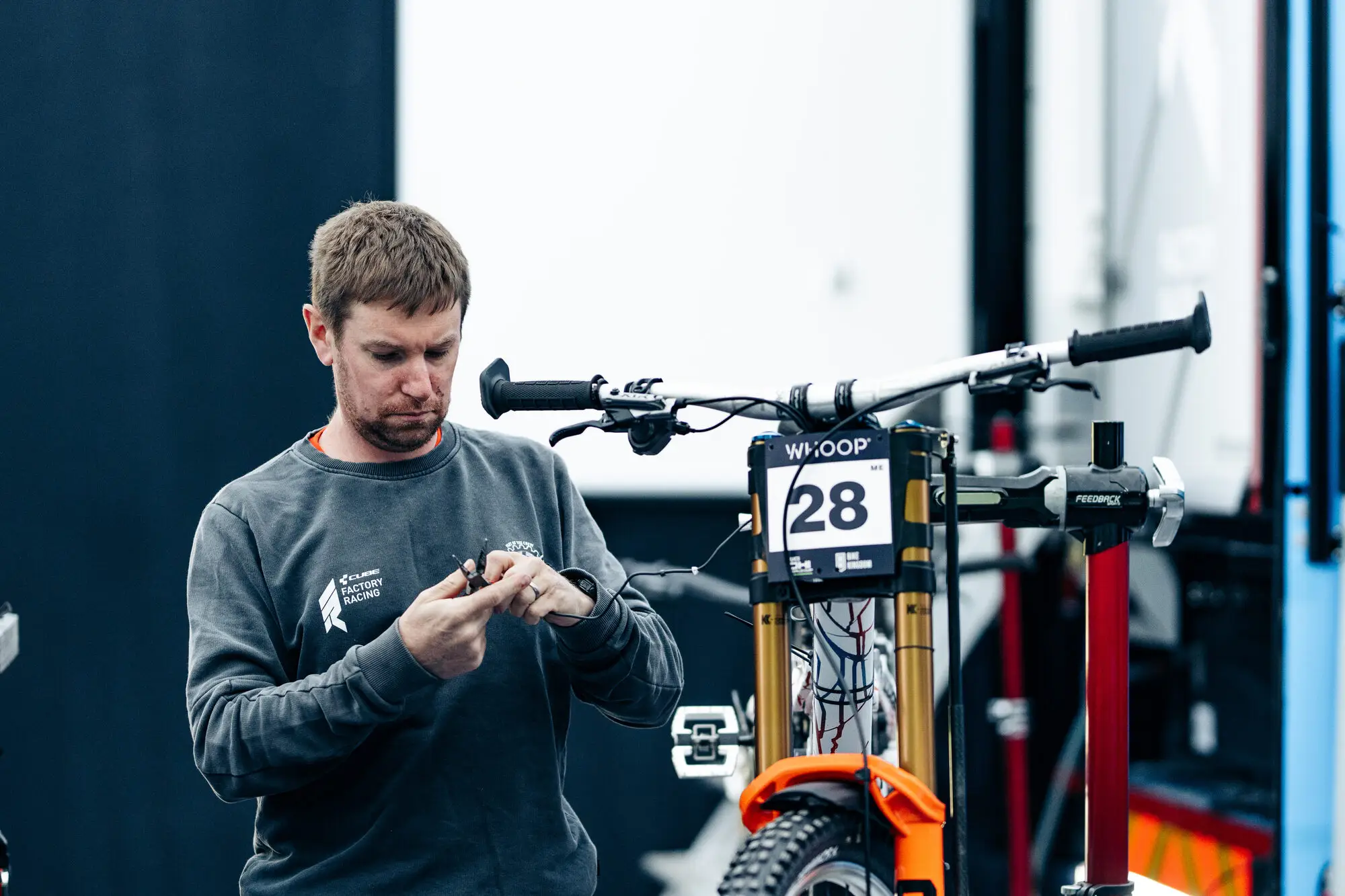 A Cube Factory Racing mechanic preparing a downhill race bike in the team pit at a UCI Downhill World Cup round.