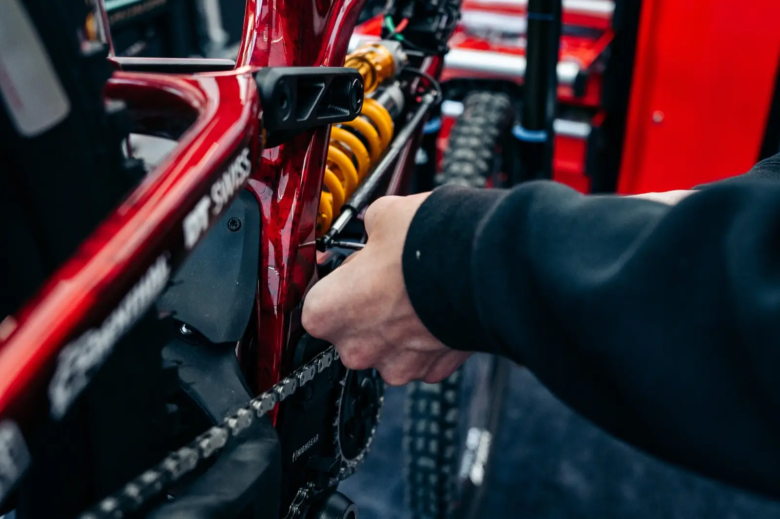 A technician's hands fitting a BYB Telemetry linear sensor alongside the coil shock of a downhill mountain bike.