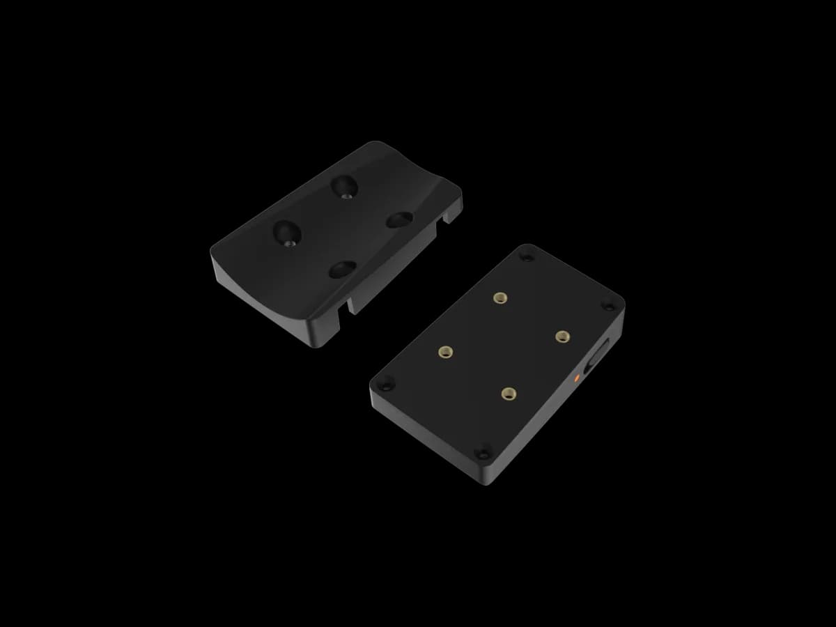 Two black mounting plates for the BYB Chrono shown apart, one face up and one face down, with brass threaded inserts and a keyed rail that lets the two slide together.
