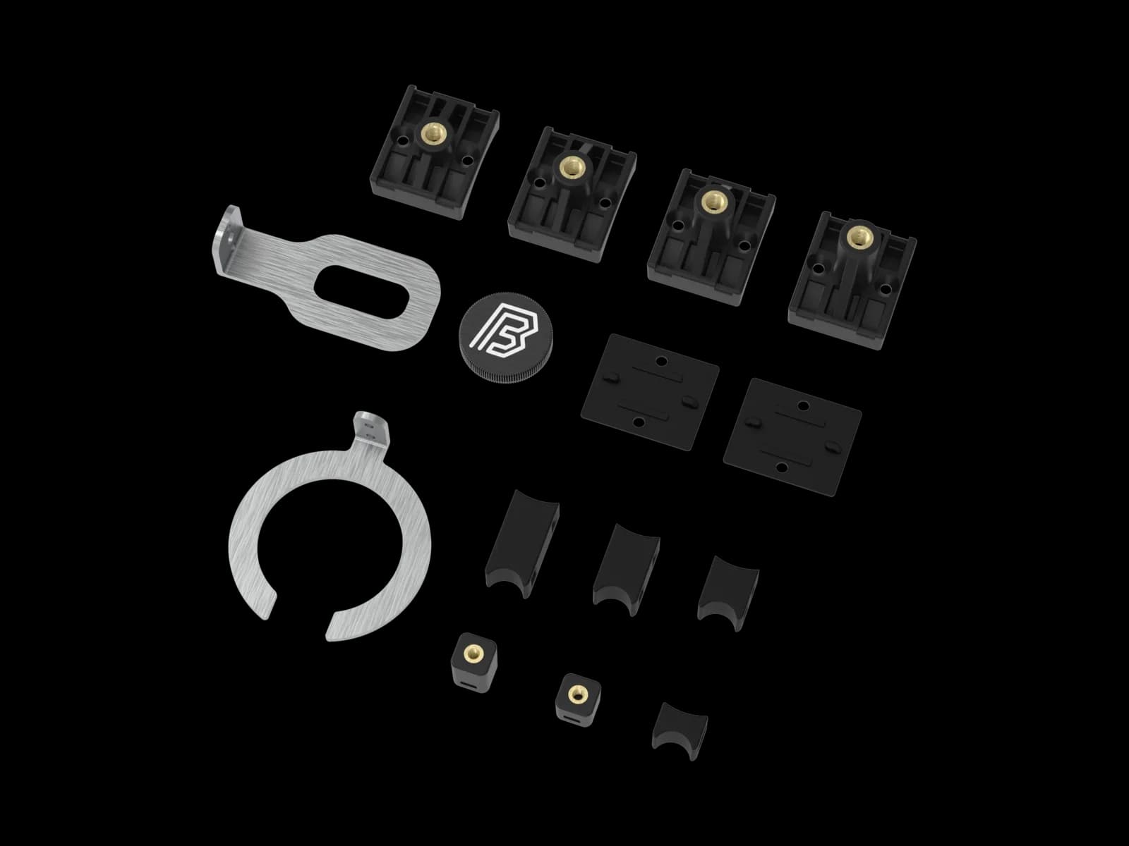The MTB mountings full kit laid out flat: four black plastic fork mountings with brass inserts, two flat anti-slip pads, a slotted steel fork bracket, a BYB-marked aluminium fork cap, a C-shaped steel shock bracket, and six small plastic shock mountings.