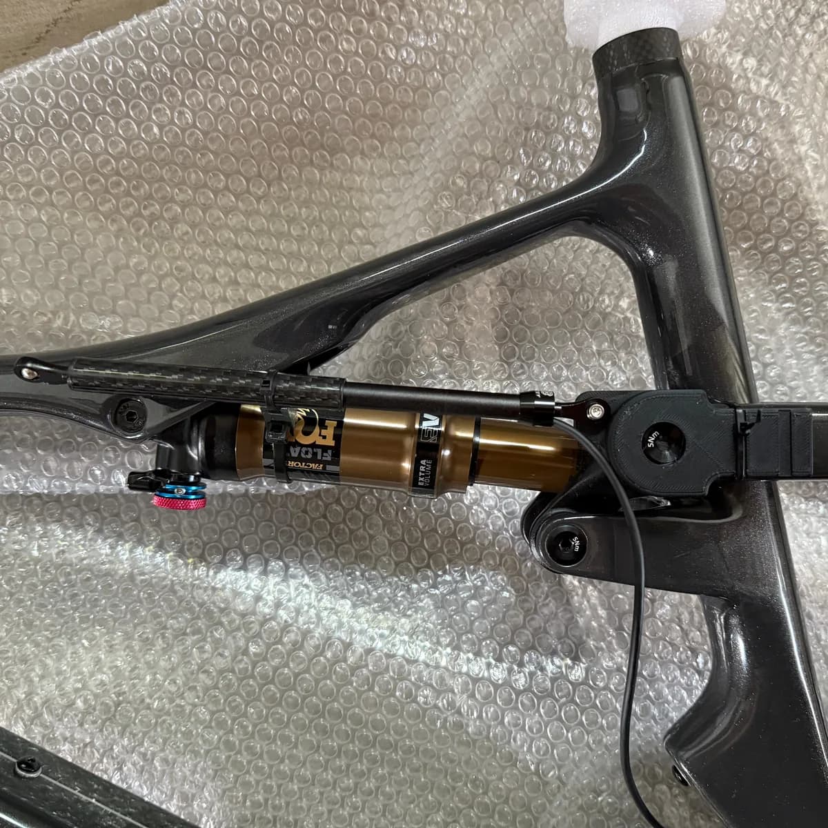 A Cannondale Scalpel carbon frame on a bench, with the printed bracket bolted beside the Fox Float Factory rear shock and the sensor cable running away from it.