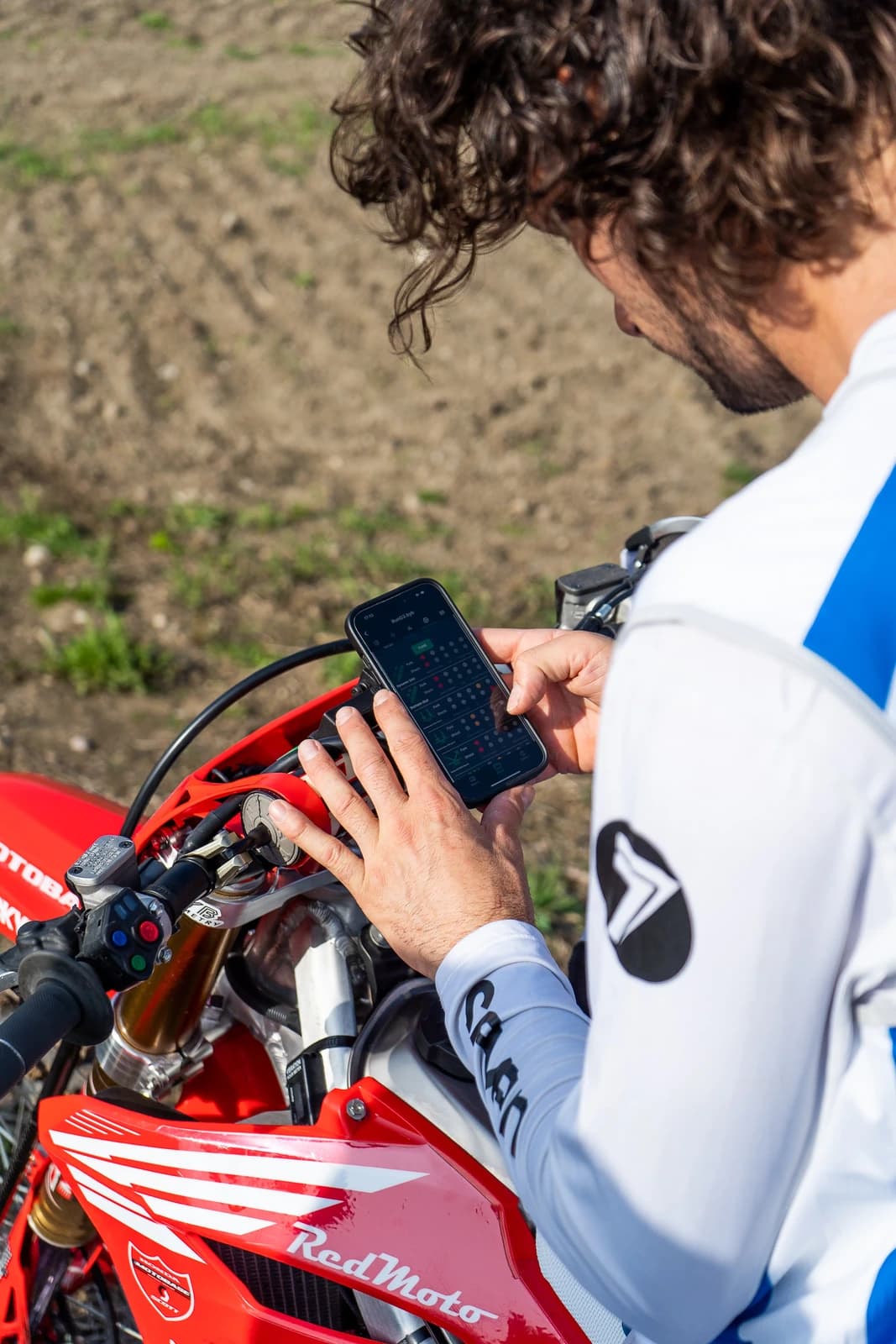 The BYB Telemetry smartphone app held in front of a motocross bike during a session